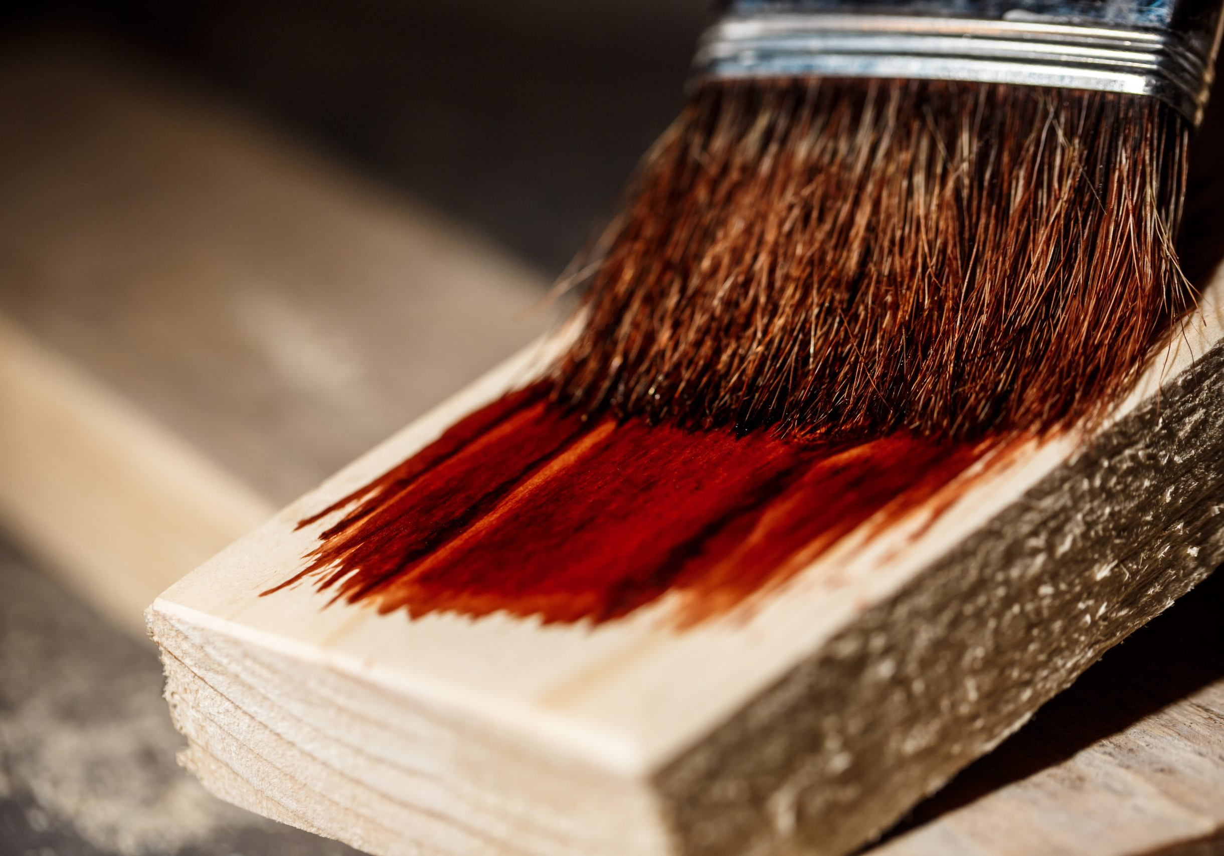 Close up photo of painting wood in brown color over dark background. Copy space.